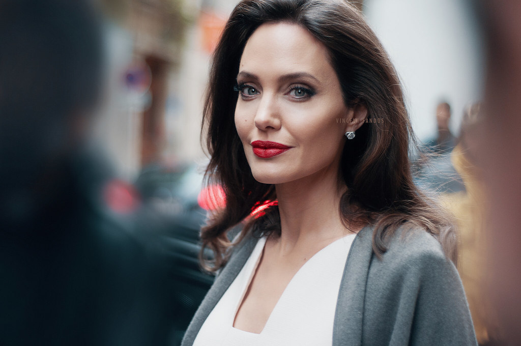 Angelina Jolie looking elegantly at the camera, featuring bold red lips and soft waves in her hair.