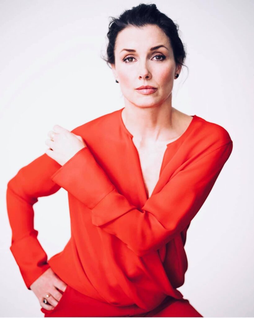 Bridget Moynahan poses in a vibrant red outfit, showcasing elegant style.