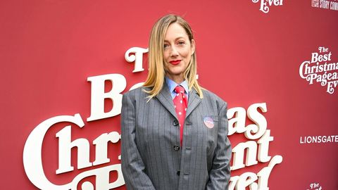 Judy Greer appears at the launch event for The Best Christmas Pageant Ever, dressed in a sharp gray suit and red tie, embodying a festive spirit.