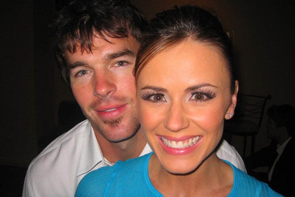 Trista sutter and Ryan Sutter smiling together at an event, with Ryan standing behind Trista.