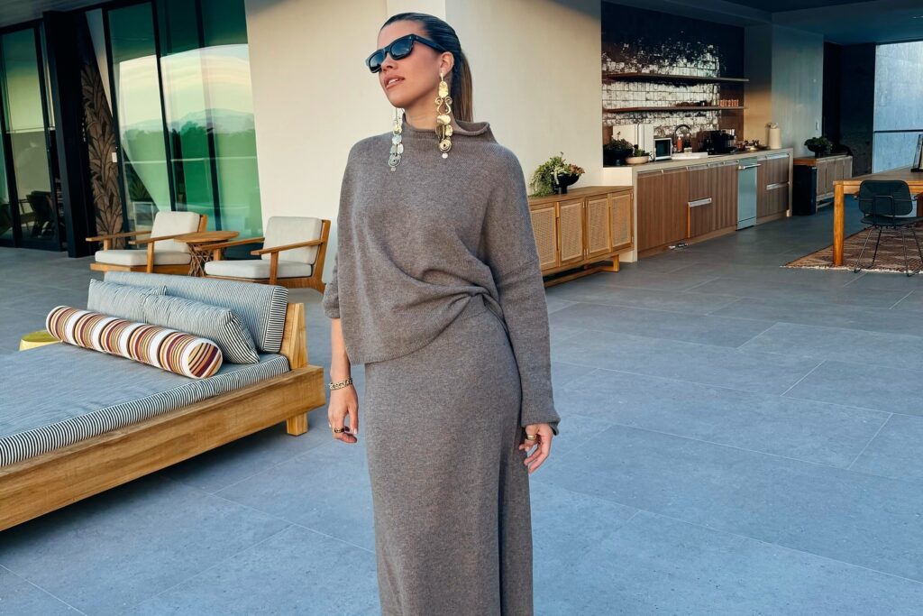 Sofia Richie Grainge poses outdoors in a stylish brown outfit with oversized earrings and sunglasses, showcasing modern elegance.