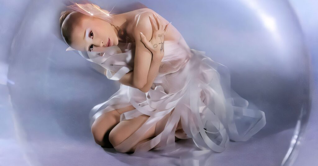 Ariana Grande in ethereal white ribbons curled inside a translucent bubble on a soft lavender background, gazing toward camera.