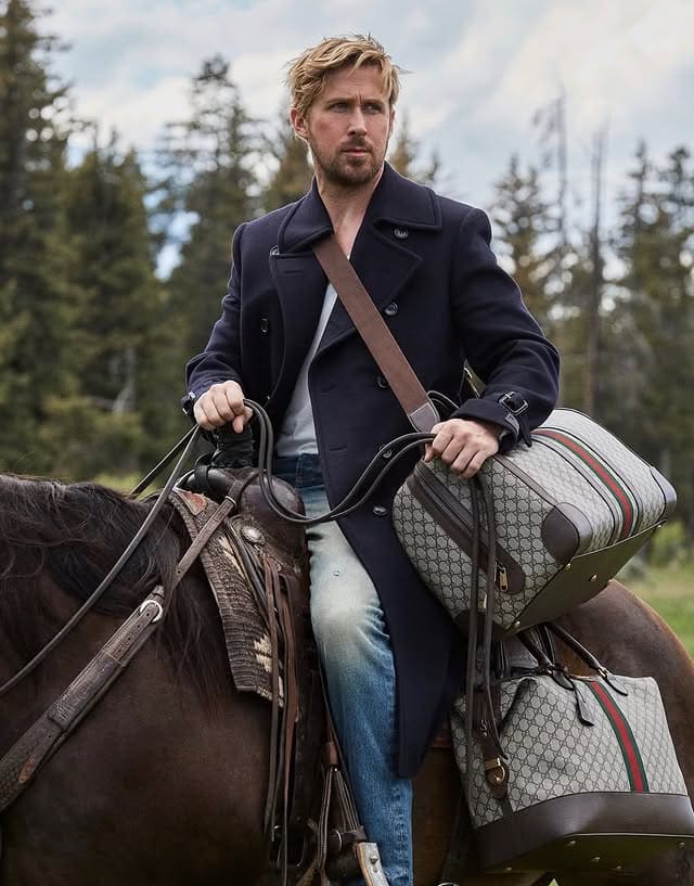  Ryan Gosling riding a horse, wearing a dark navy coat and carrying luxury Gucci bags in an outdoor forest setting.