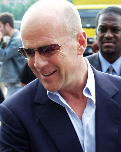 Bruce Wills in a suit and sunglasses outdoors