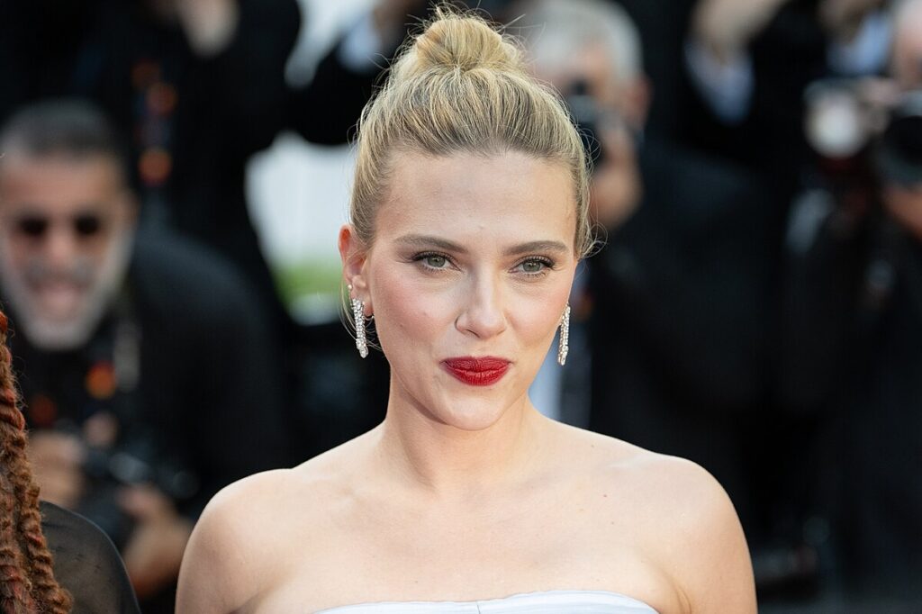 scarlett johansson at a formal event wearing elegant jewelry and bright lipstick, posing for cameras.