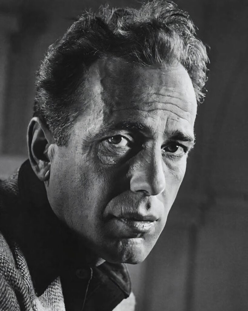 A high-contrast, black and white close-up portrait of Humphrey Bogart, showing detailed facial textures and a thoughtful, intense expression.