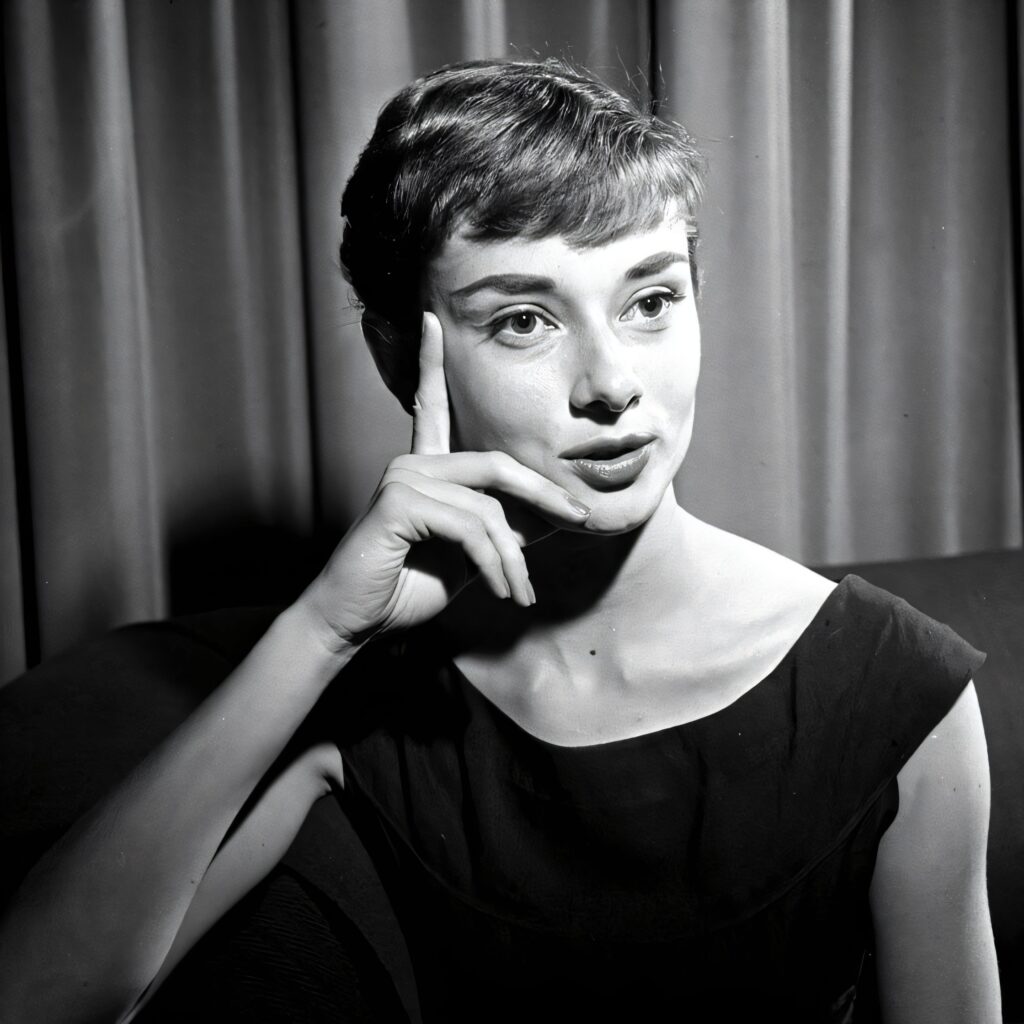 A black and white candid photo of Audrey Hepburn looking down while reading a magazine titled "Eau de Lanvin for Men."