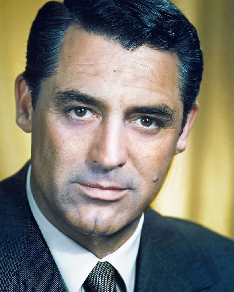 A classic black and white studio portrait of Cary Grant in a military uniform, featuring a side-parted hairstyle and a slight, charismatic smile.